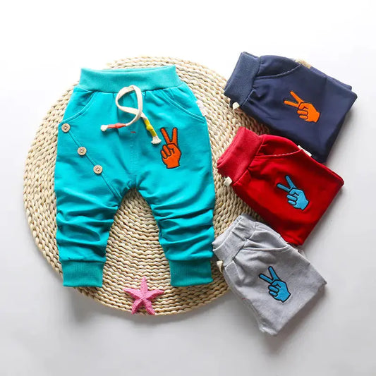 vier katoenen babybroekjes op rieten display – minimalistisch, stijlvol en praktisch.
